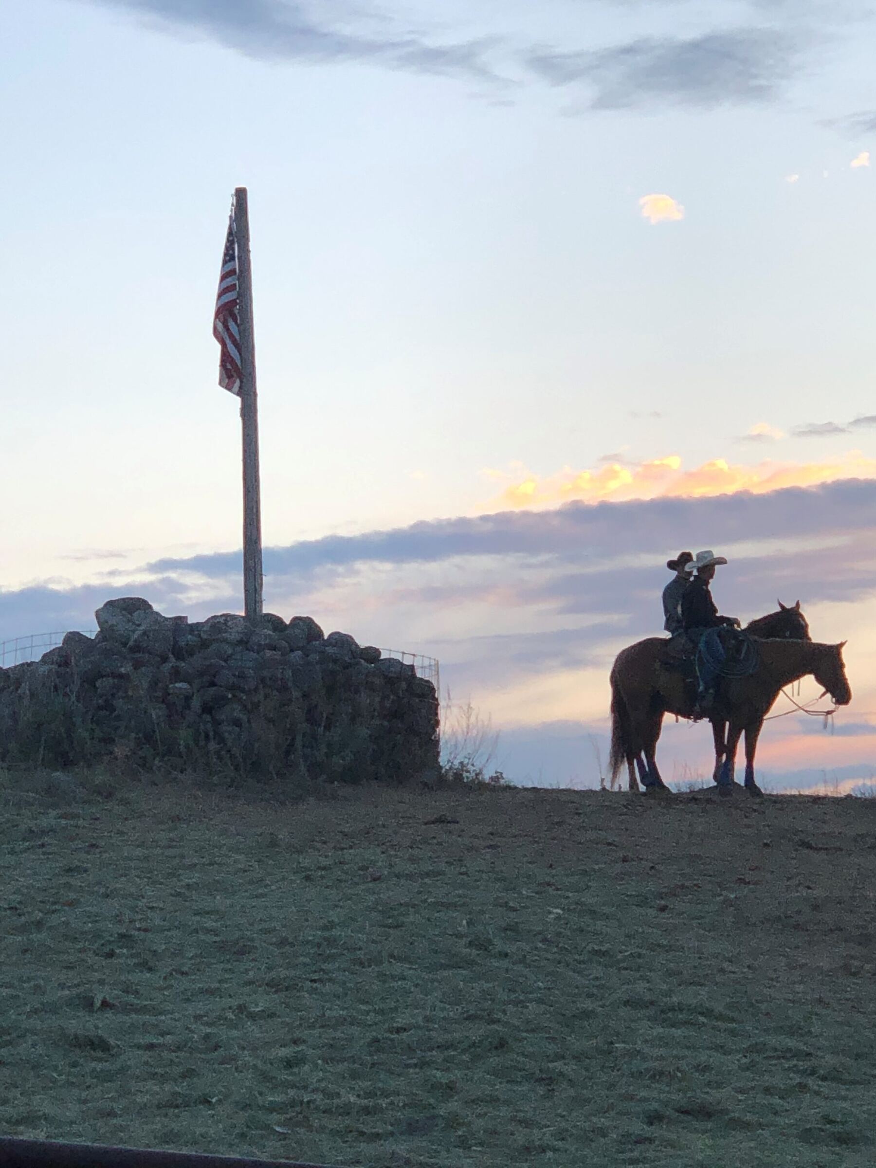 Two riders on horseback at sunset